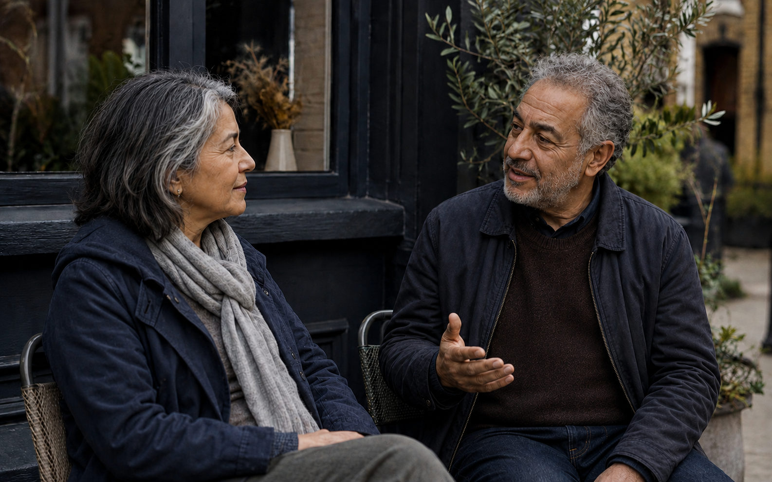 Two adults talking outside a neighbourhood cafe.